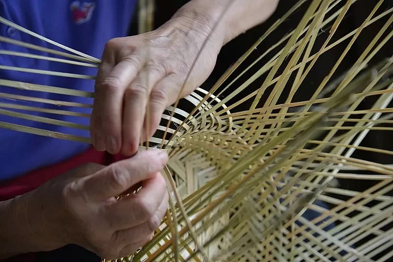 Skilled workers producing handcrafted rattan lighting in a specialized factory